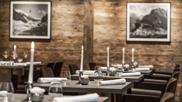 Ein elegantes Restaurant mit Holzwänden und stimmungsvollem Licht. Die Tische sind geschmackvoll gedeckt und laden zum Verweilen ein.