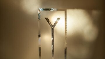 Ein minimalistisches Schild mit dem Buchstaben "Y". Das Licht bricht sanft durch die glatte Oberfläche.